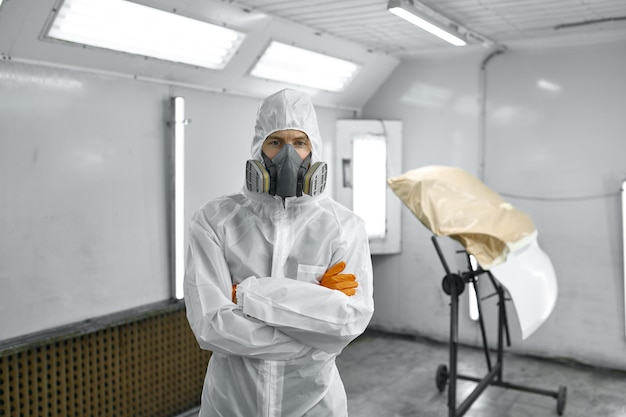 Car mechanic in mask in paint chamber