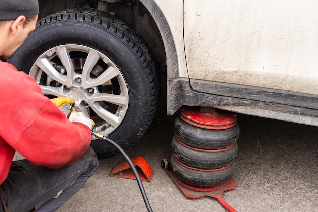 Photo car mechanic removing wheel nuts to check brakes