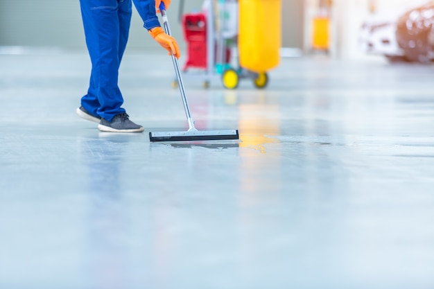 Car mechanic repair service center cleaning using mops to roll water from the epoxy floor. In the car repair service center.