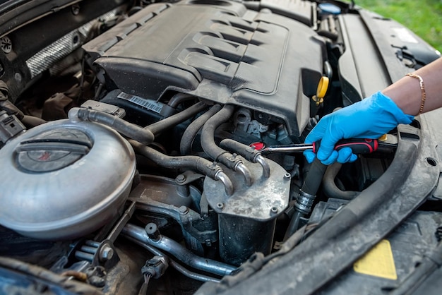 Car mechanic or repairman repairs a car engine by hand in a car workshop with a wrench