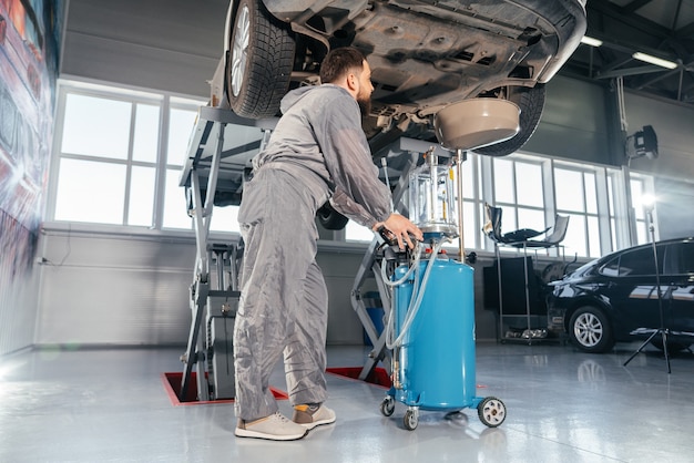 Car Mechanic Replacing Oil in Motor Engine. Auto service shop