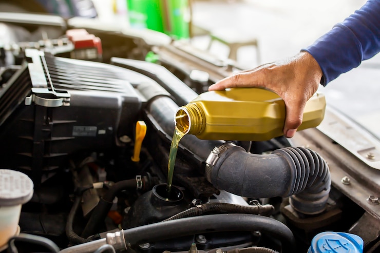 Photo car mechanic replacing and pouring fresh oil into engine at maintenance repair service station.