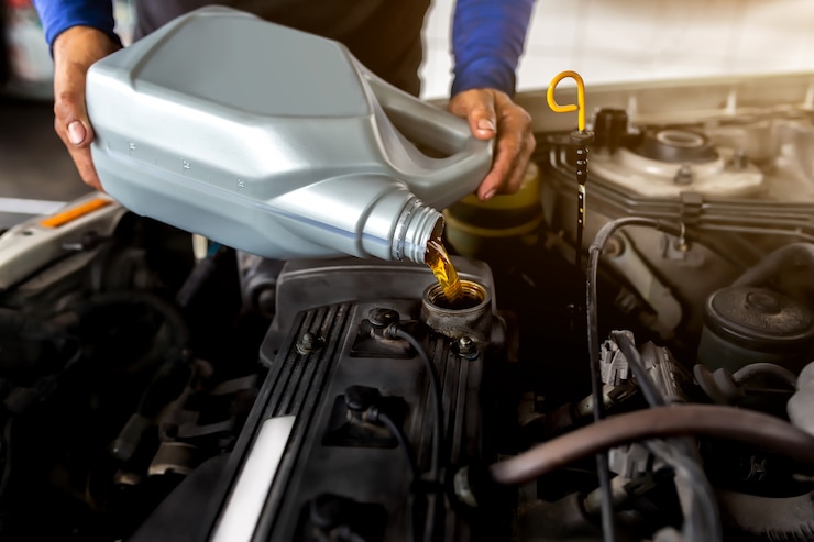 Photo car mechanic replacing and pouring fresh oil into engine at maintenance repair service station.