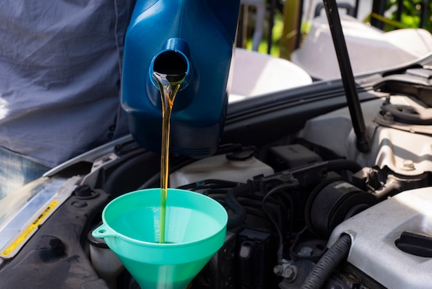 Car mechanic replacing and pouring fresh oil into engine at maintenance repair 