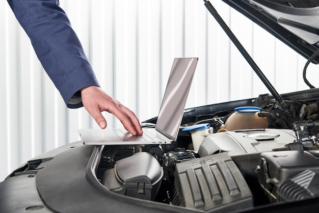 Meccanico di automobile che utilizza computer nell'officina riparazioni automatica