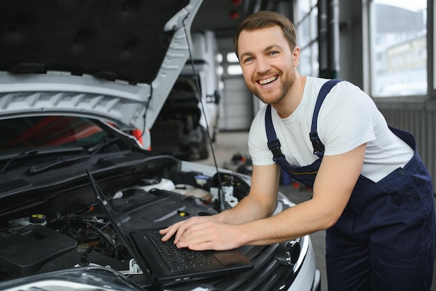 コンピューターのラップトップを使用して、修理および修理のために自動車のエンジン部品を診断およびチェックする自動車整備士