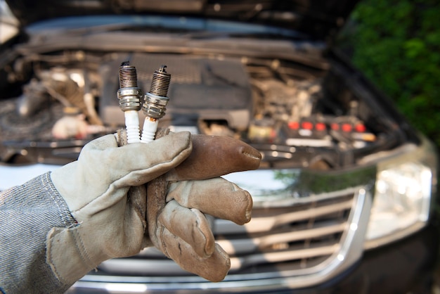 Car mechanic wearing gloves holding old spark plugs