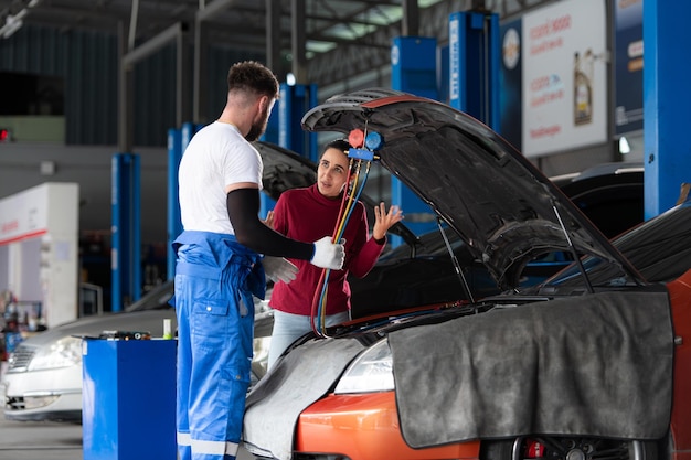 Car mechanic working in an auto repair shop explain to customer