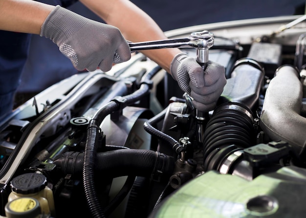 Car mechanic working on car engine, car maintenance concept.