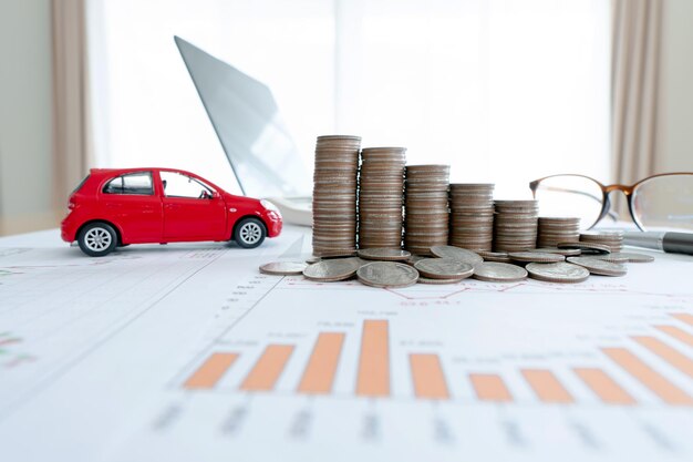 Car model and financial graph with coins and laptop background