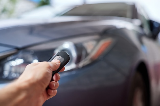 The car owner holds in his hand a remote control device for keyless entry