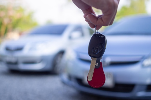 car owner's hand holding the delivery key to buyers Concept of selling cars and giving keys