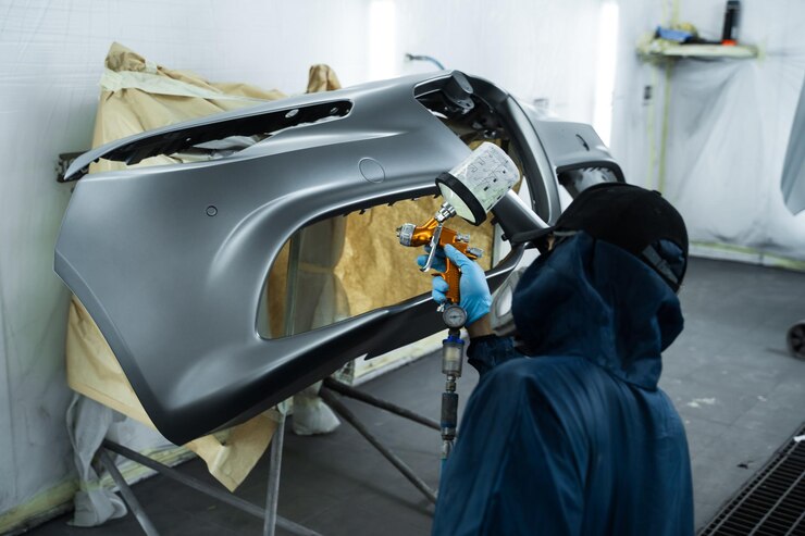 Car painter is applying lacquer on car using LVLP spray gun Putting lacquer on metal to give surface smooth appearance