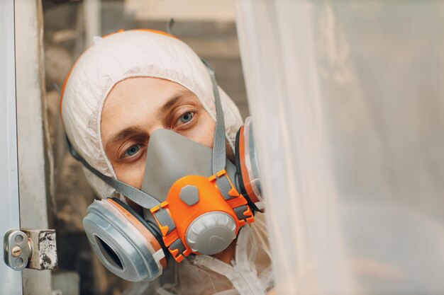 Foto verniciatore di auto in abiti protettivi e maschera respiratoria veicolo di verniciatura