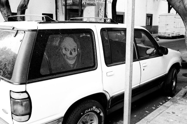 Photo car parked by roadside with skull on glass window