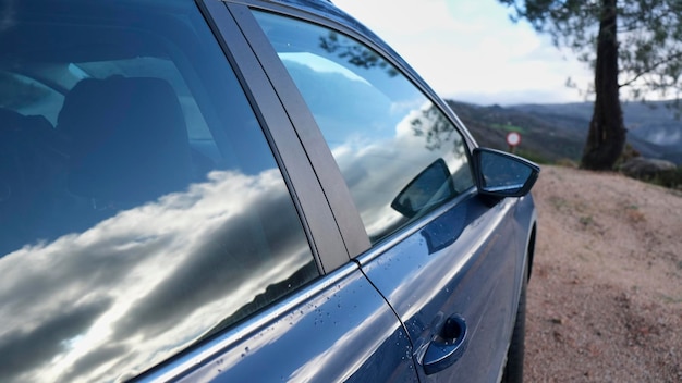 car parked in nature with the reflection of clouds in the glass