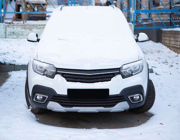 A car parked on the street is covered in fresh white snow