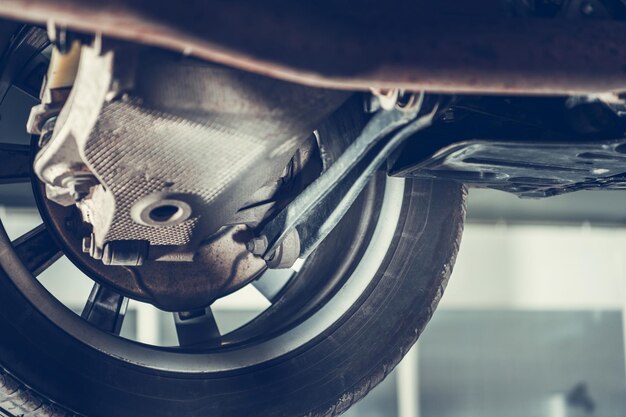 Photo car raised on lift in auto repair shop