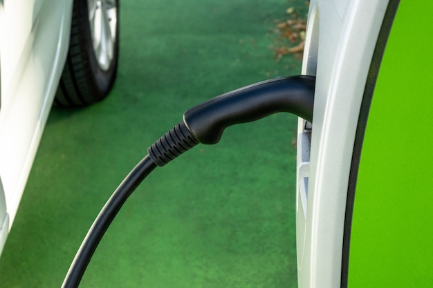 A car recharges its electric batteries inside a private garage\
with its own charging station, detail of the connected plug.