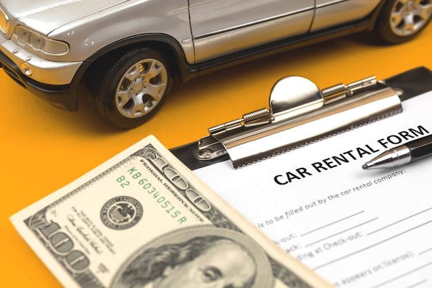 Car rental document contract. Car rental service concept photo. Desktop with car toy, clipboard, money and pen