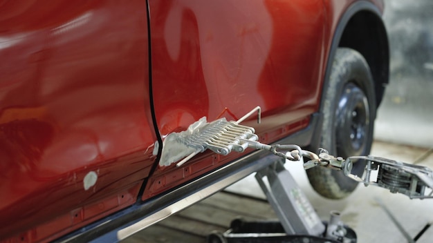 Foto riparazione dell'auto dopo l'incidente restauro della carrozzeria della carrozzeria dell'officina riparazioni dell'auto tirando fuori le ammaccature