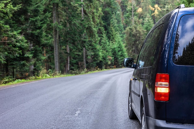 Auto su strada in una foresta in una zona montuosa il concetto di un viaggio su strada