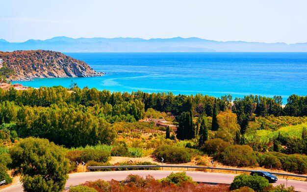 Car at the road at Villasimius with Mediterranean Sea in Sardinia Island in Italy summer. Transport driving on highway of Europe. Holiday View on motorway. Cagliari province. Mixed media.