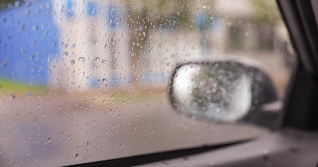 A car's side mirror with raindrops on it.
