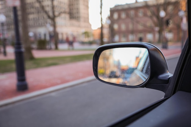 A car's side view mirror shows a street in the background.