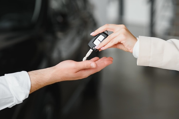 Car sale Dealer giving key to new owner in auto show or salon closeup