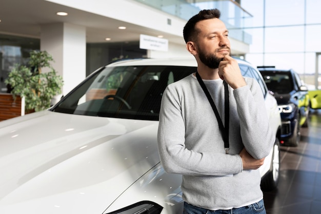 Car sales manager at car dealership looking ahead thoughtfully