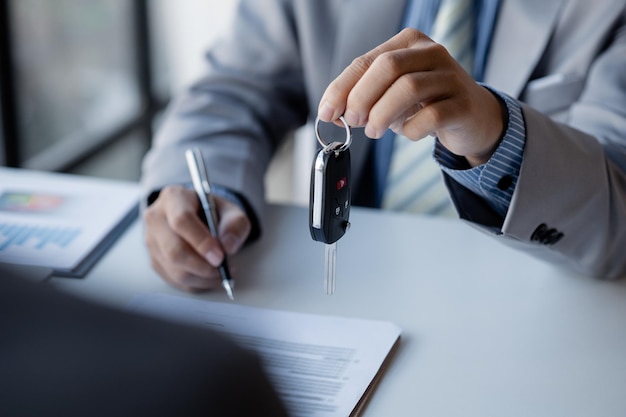 The car salesman hands the key to the customer after discussing the details and signing the purchase agreement selling the car selling the car from a major dealer Vehicle sales concept