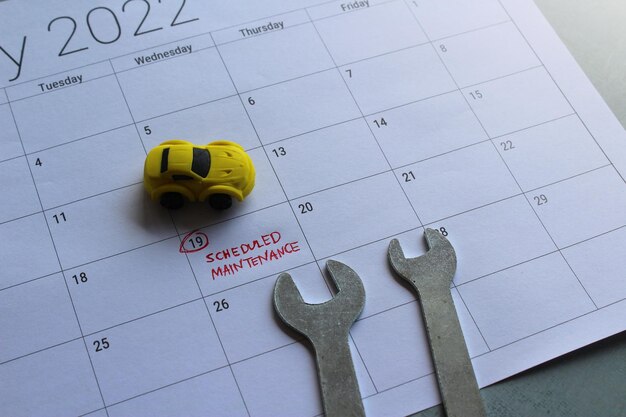 Car scheduled maintenance concept. Toy car, spanner and calendar with text SCHEDULED MAINTENANCE