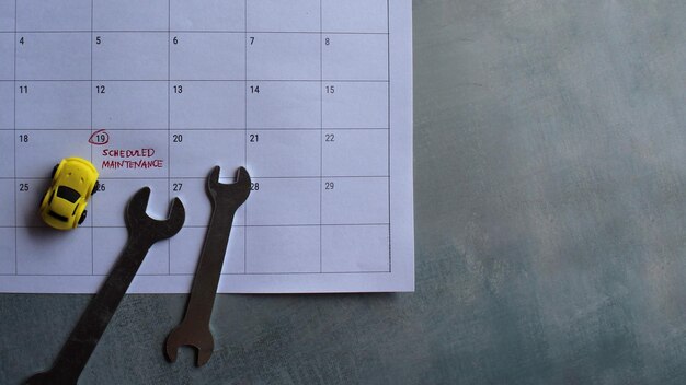 Car scheduled maintenance concept Toy car spanner and calendar with text SCHEDULED MAINTENANCE