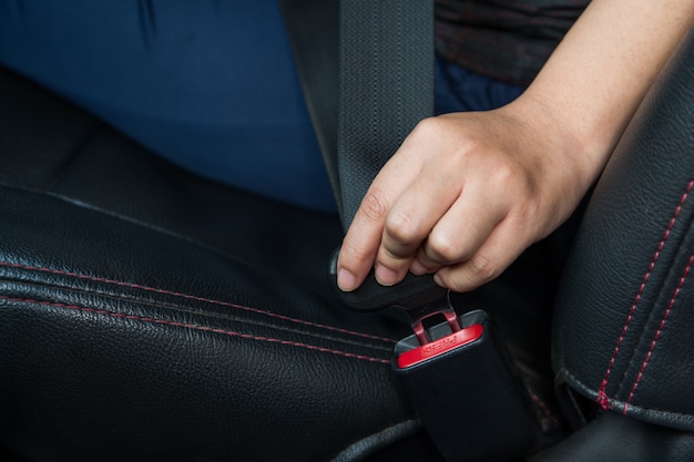 カーシートベルト。女性は車のシートベルトを固定します安全な運転。手持ちの安全ベルト。