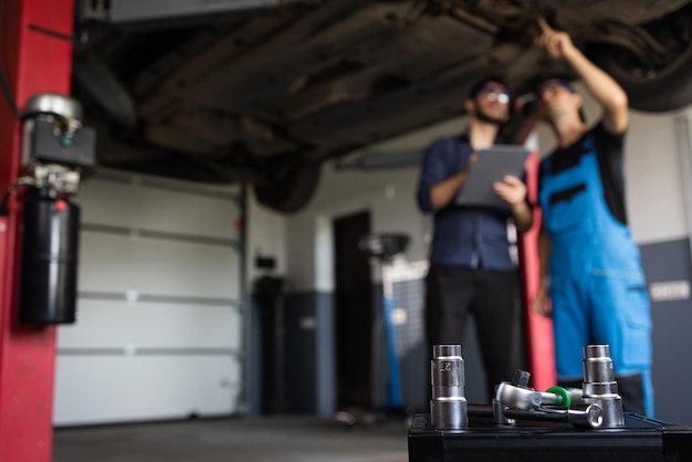 Car service employees inspect the bottom and skid plates of the car manager checks data on notebook