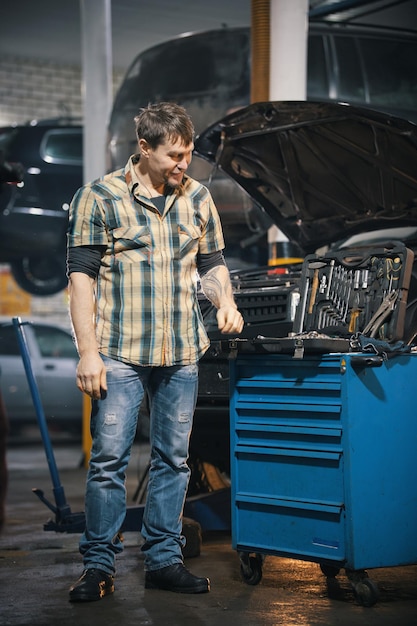 Photo car service mechanic man standing next to a tool case