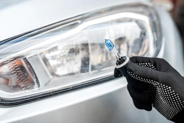 Car service men holding halogen h7 lamp for repair or change in headlight