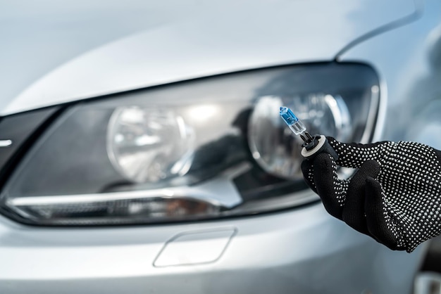 Car service men holding halogen h7 lamp for repair or change in headlight