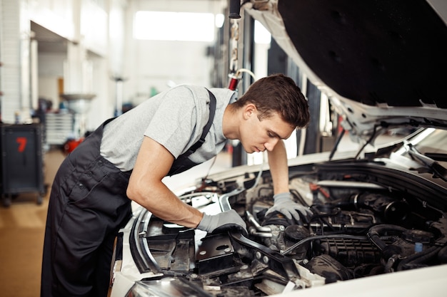 At a car service: a qualified mechanic is dealing with a car engine.