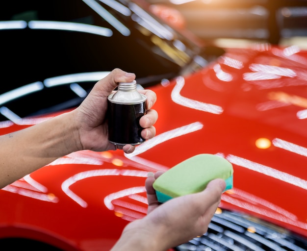 Lavoratore di servizio dell'automobile che applica rivestimento nano su un dettaglio dell'automobile