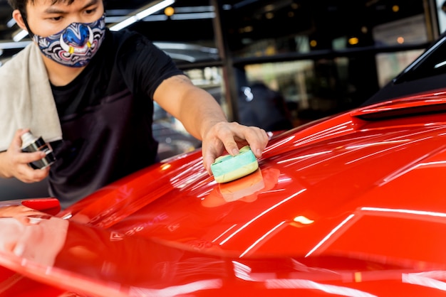 Lavoratore di servizio dell'automobile che applica rivestimento nano su un'automobile