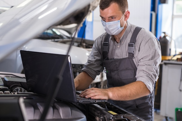 Car service worker carries out diagnostics and car repairs in the room.