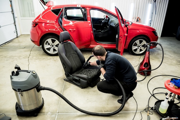 Photo car service worker cleaning car seat with vacuum cleaner