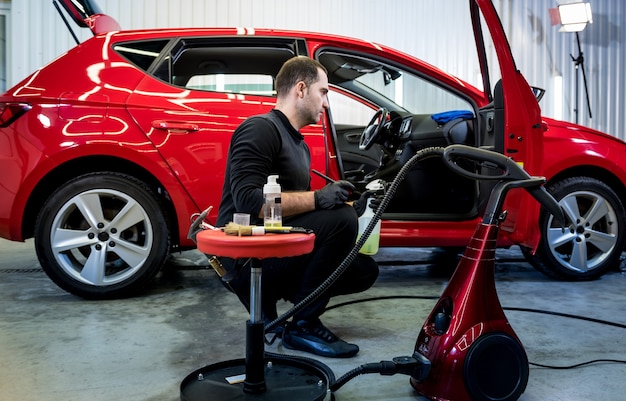 Car service worker cleans interiror with special brush