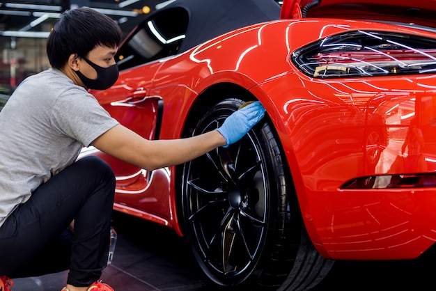 Car service worker polishing car wheels with microfiber cloth.