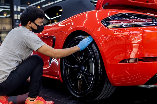 Car service worker polishing car wheels with microfiber cloth.