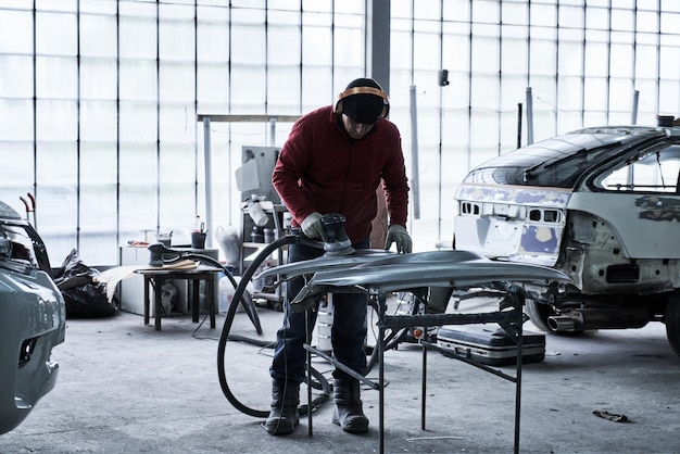 Car service worker repairs restores car