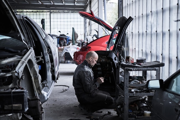 Car service worker repairs restores car