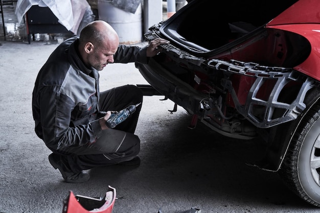 Car service worker repairs restores car